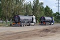 Two tractor-trailers with tanker trucks are standing on the side