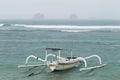 Two traditional Bali fishing boats on big waves in storm and raining