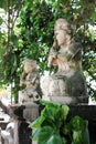 Two traditional, stone, old, Balinese statues depicting deities adorn the fence columns. They are made of light stone.