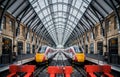 Two trains symmetrical mirrored in London Kings Cross Station deserted platforms with train waiting on each track and no passenger