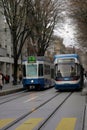 Two trams in blue color passing each other in opposite directions in city center of Zurich, on Bahnhofstrasse.