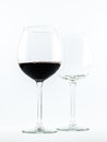 Two transparent glasses - one full of red wine and the other is empty - on a white background Royalty Free Stock Photo