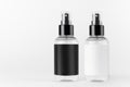 Two transparent spray bottles for cosmetics product with black, white blank labels on white background, mock up for branding. Royalty Free Stock Photo