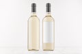 Two transparent wine bottles with blank white label and without label, on white wooden board, mock up. Royalty Free Stock Photo