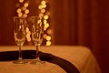 Two romantic glasses on the edge of the bed in the light of warm lights, next to a man`s tie.