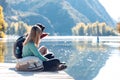 Two travel hikers sitting while man pointing something in the landscape in the lake on mountain