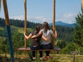 two travelers enjoying of swinging on heavenly swing and mountain view
