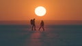 The two travelers walking through the arctic snowy field on sunset background. Royalty Free Stock Photo