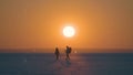 The two travelers walking through the snow field on sunset background. Royalty Free Stock Photo