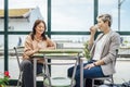 Two travelling women with luggage drinking coffee at train station Royalty Free Stock Photo