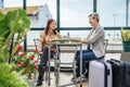 Two travelling women with luggage drinking coffee at train station Royalty Free Stock Photo