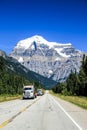Two tree transportating trucks transport on the canadian highway in front of a snowy mountain Royalty Free Stock Photo