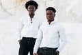 Two trendy black men, fashion portrait of African American male models, in white shirts, outdoors