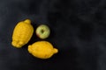Two trendy organic lemons and one Apple on a dark background.
