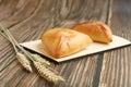 Two triangle traditional russian cabbage pies on a wooden cutting board laying on a wooden table, side view