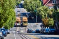 Two trollies side by side at bottom of hill with upward slope on sunny California day