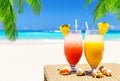 Two tropical fresh juices on white sandy beach