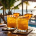 Two tropical orange cocktails with garnishes on a wooden poolside table.