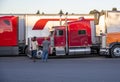 Truck drivers exchange views on the strengths and weaknesses of their big rigs semi trucks standing on truck stop