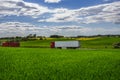 Trucks transporting goods on the asphalt road between green fields in a rural landscape under a cloudy blue sky Royalty Free Stock Photo