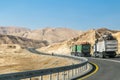 Trucks heading up on highway to the rocky mountains in the Negev desert. Road with tracks. Royalty Free Stock Photo