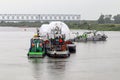 Two tugs and a barge with a large load