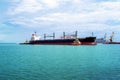 Two tugs moor the bulk carrier at the seaport. Black cargo ship mooring at the port. Cargo transportation by water.