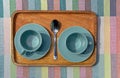 Two turquoise coffee cups on a wooden tray