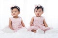 Two twin babies in pink dress on bed Royalty Free Stock Photo