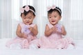 Two twin babies in pink dress on bed Royalty Free Stock Photo