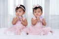 Two twin babies in pink dress on bed Royalty Free Stock Photo