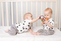 Two twin babies play in the crib, the concept of the relationship of children of brother and sister, the child takes the toy from Royalty Free Stock Photo