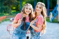 Two  twin girls hugging and laughing in denim overalls with lollipops Royalty Free Stock Photo