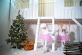 Two twin sisters in doggie dresses at the front of a white wooden house are playing. Girls and poodles decorated for Christmas and Royalty Free Stock Photo