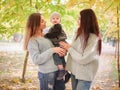 Two twin sisters, stand in an autumn parkwatching a little boy, one of whom is holding them. Royalty Free Stock Photo