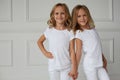 Two twin sisters in white clothes holding hands isolated on a white background. The concept of childhood lifestyle Royalty Free Stock Photo