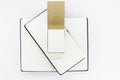 Two unfold black notebooks lie on top of each other and open notepad with blank light beige pages. Top view. White back Royalty Free Stock Photo