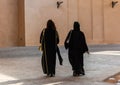 Two unidentifiable Arabic women wearing traditional Islamic black dress walking away