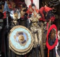Two unidentified men and woman dress elaborate fancy dresses with gold masks, red and black feather hats during Venice Carnival