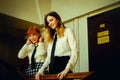 Two uniformed female students standing on a university staircase, laughing joyfully together. Friendship. Happiness of the end of