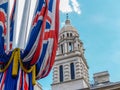 Two Union Jack flags draped from pole tied with gold braid rope and Romanesque dome in background from The Mall Royalty Free Stock Photo