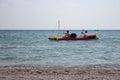 Two unknown men in rubber boat with vessels and ukrainian flag sailing along seashore. Vacation and recreation concept.