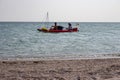 Two unknown men in rubber boat with vessels and ukrainian flag sailing along seashore. Vacation and recreation concept.