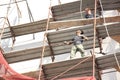 Two unprotected construction workers on the scaffold during building facade reconstruction, an unsafe, hazard and dangerous