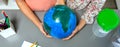 Two unrecognizable female students holding handmade globe world earth