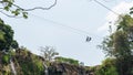 Two unrecognizable people seen from afar descending on canopy in front of a waterfall in Matagalpa, Nicaragua