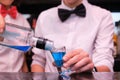 Two unrecognizable waitress serving a blue shot in a bar.