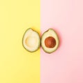 Two upsidedown halves of avocado on a pastel yellow and pink background