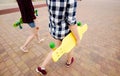 Two urban girls with longboards wearing checkered shirts going along the street in the city Royalty Free Stock Photo