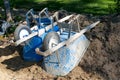 Two used, blue, dirty wheelbarrows turned upside down in the dirt